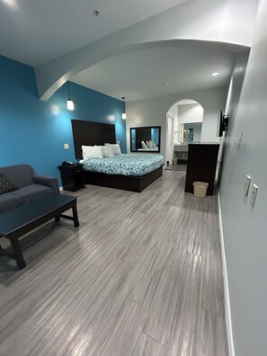 A modern bedroom with a bed, a sofa, a desk, and a mirror.