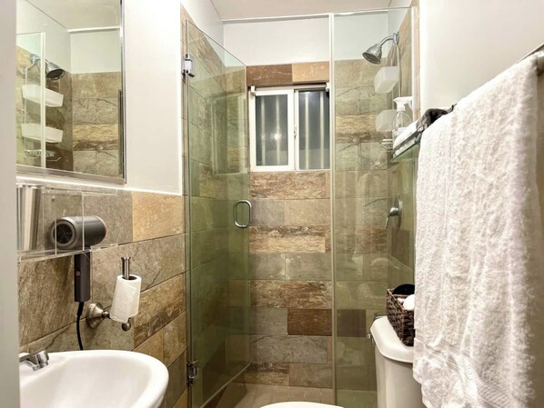 A modern bathroom with a glass-enclosed shower, a toilet, and a sink.