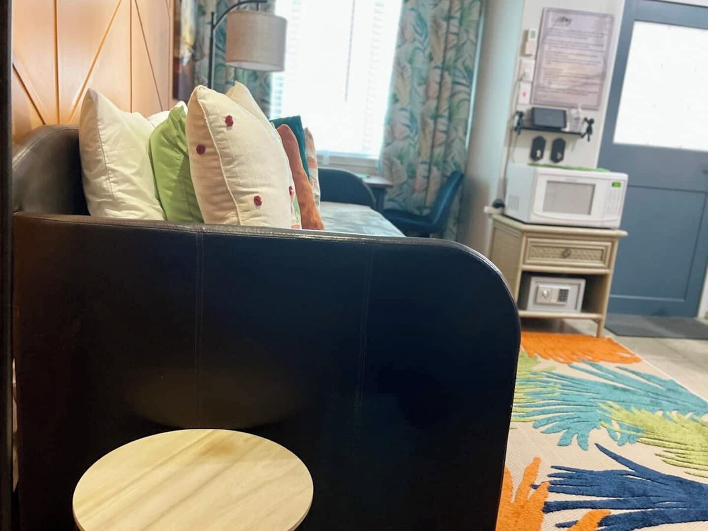 Une pièce avec un canapé, des coussins, un four à micro-ondes et un tapis à motifs.