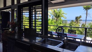 A kitchen with a view of the ocean and palm trees. - Kaila Na Ua Resort (Korotogo)