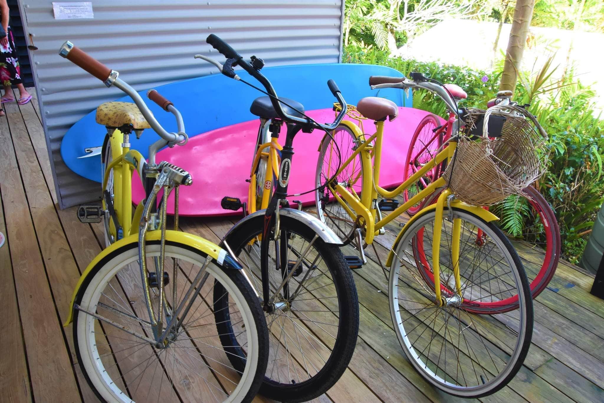 A wooden deck with two bicycles and two surfboards.