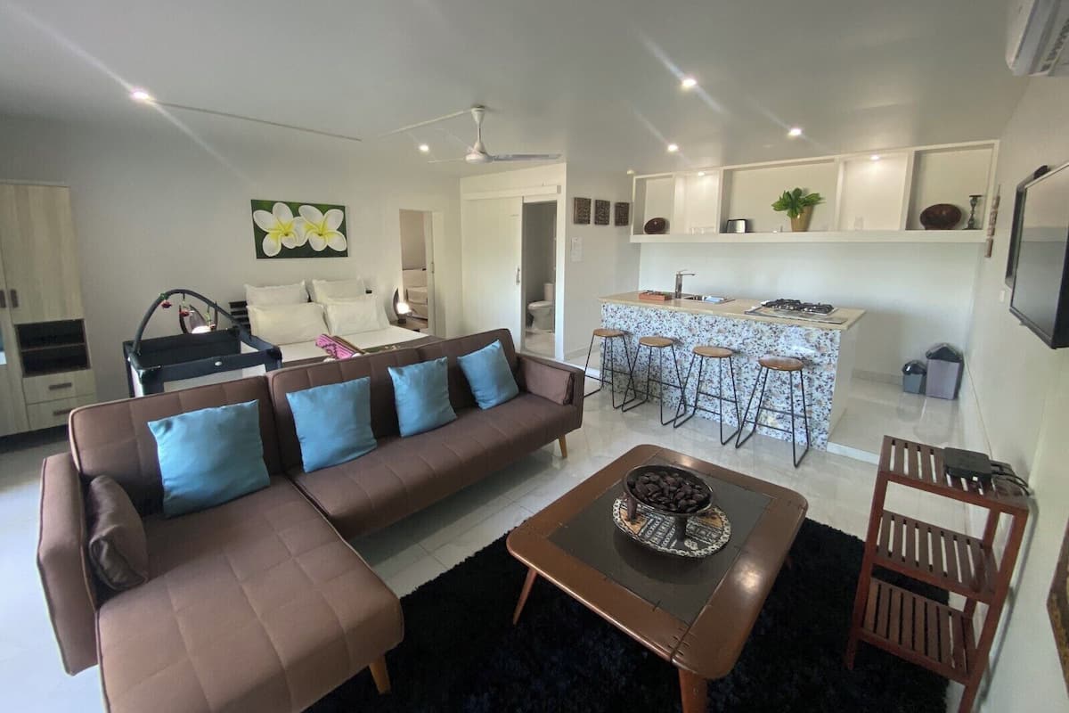 Ein modernes Wohnzimmer mit Sofa, Couchtisch und Küchenbereich mit Barhocker.