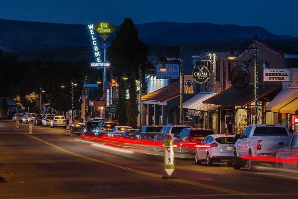 A street lined with vintage-style buildings, including a store with a neon sign reading "WELCOME" and another with "Old Town General Store."