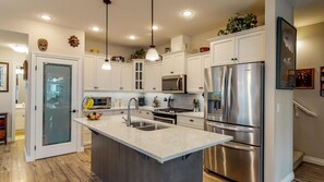 A modern kitchen with white cabinets, stainless steel appliances, and a central island with a sink.