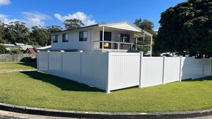 A two-story house with a covered porch and a white fence.