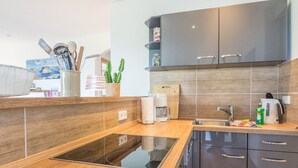 Une cuisine moderne dotée d’une cuisinière intégrée, de meubles de couleur sombre et d’un plan de travail en bois.