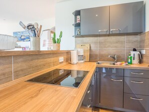 Eine moderne Küche mit Einbauherd, dunklen Schränken und einer Holzausziehtafel.