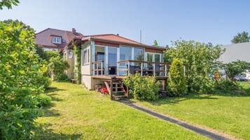 Ein zweistöckiges Haus mit Balkon, umgeben von einem gepflegten Rasen und Bäumen.