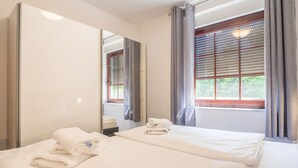 Ein Hotelzimmer mit zwei Betten, einem großen Spiegel und einem Fenster mit Jalousien.