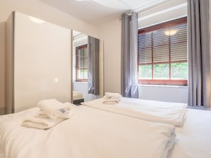 Habitación de hotel con dos camas, un espejo grande y una ventana con persianas.