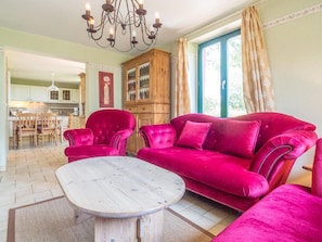 A living room with a red velvet sofa, a wooden coffee table, and a chandelier.