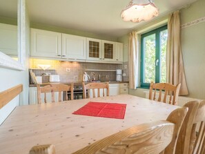A kitchen with white cabinets, a wooden table, and a red placemat.