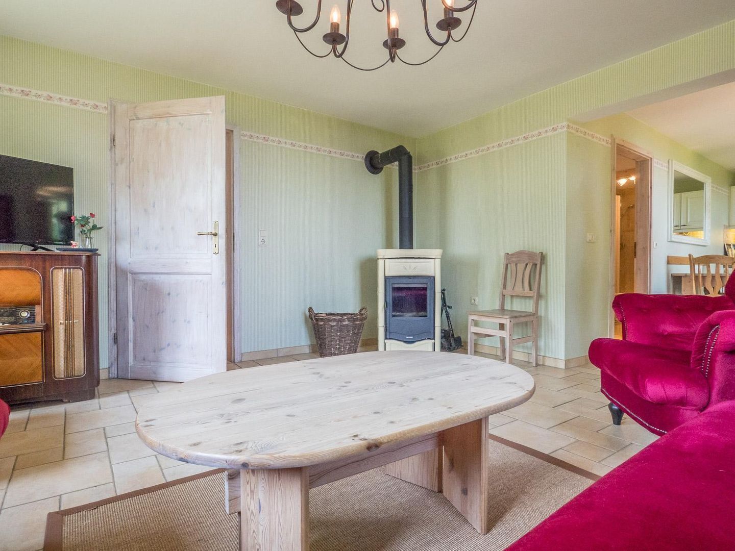 Una sala de estar con una mesa de madera, un sofá rojo, un televisor y una chimenea.