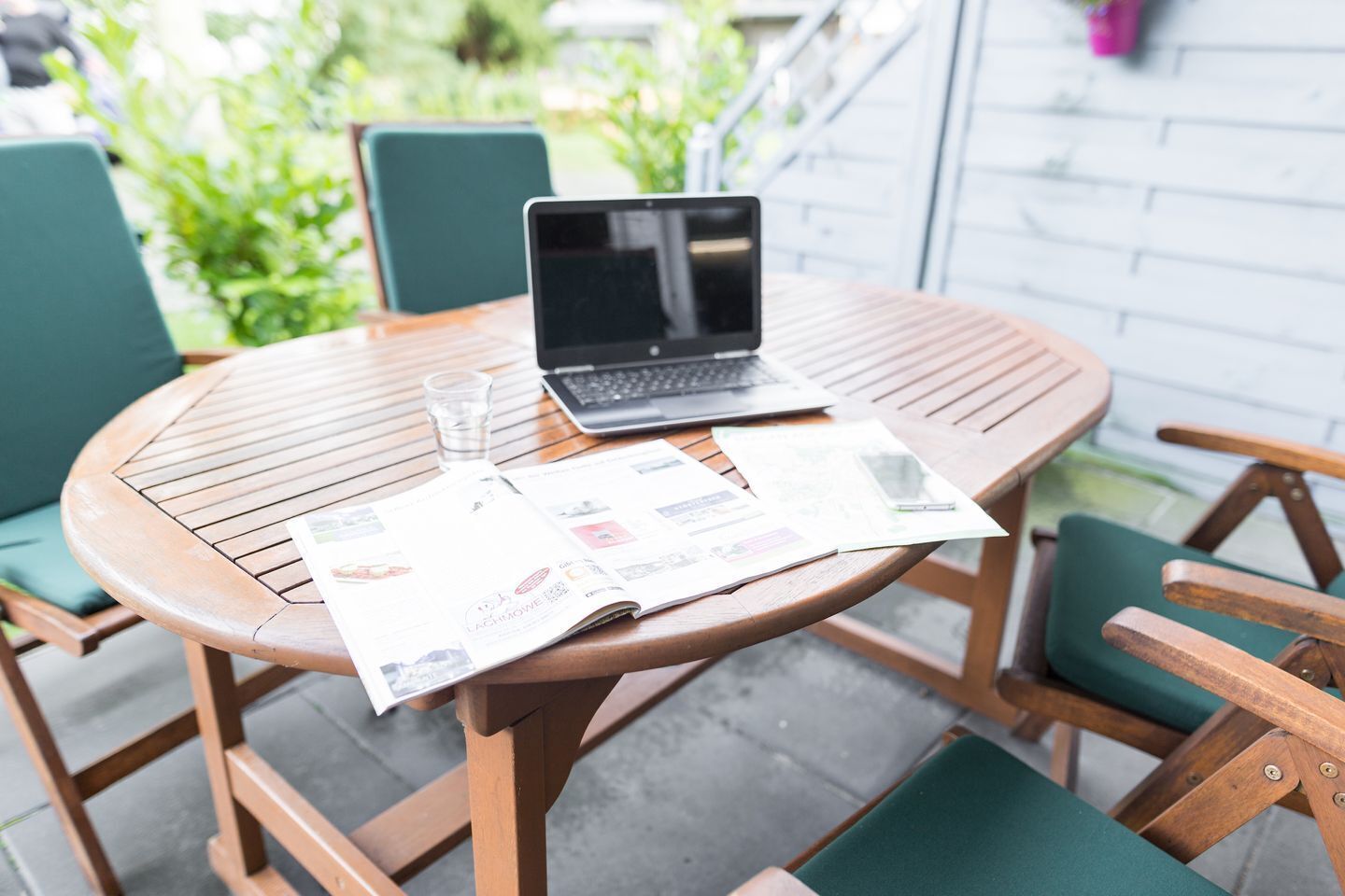 Une table ronde en bois, sur laquelle se trouvent un ordinateur portable, un verre d’eau et un menu.