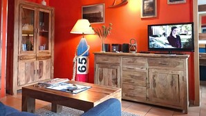 A living room with a red wall, wooden cabinets, a television, and a lamp.
