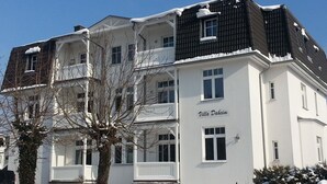 A multi-story building named "Villa Dahaim" with a white facade, balconies, and a snow-covered roof.