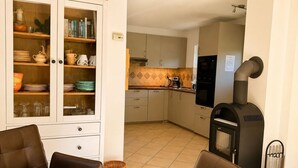 A modern kitchen with a built-in stove, cabinets, and a dining area with leather chairs. - Vacation home Emma - Apartment 2 (Lohme)