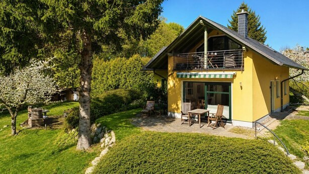A two-story house with a balcony, surrounded by a well-maintained garden and trees. - Vacation home Emma - Apartment 2 (Lohme)