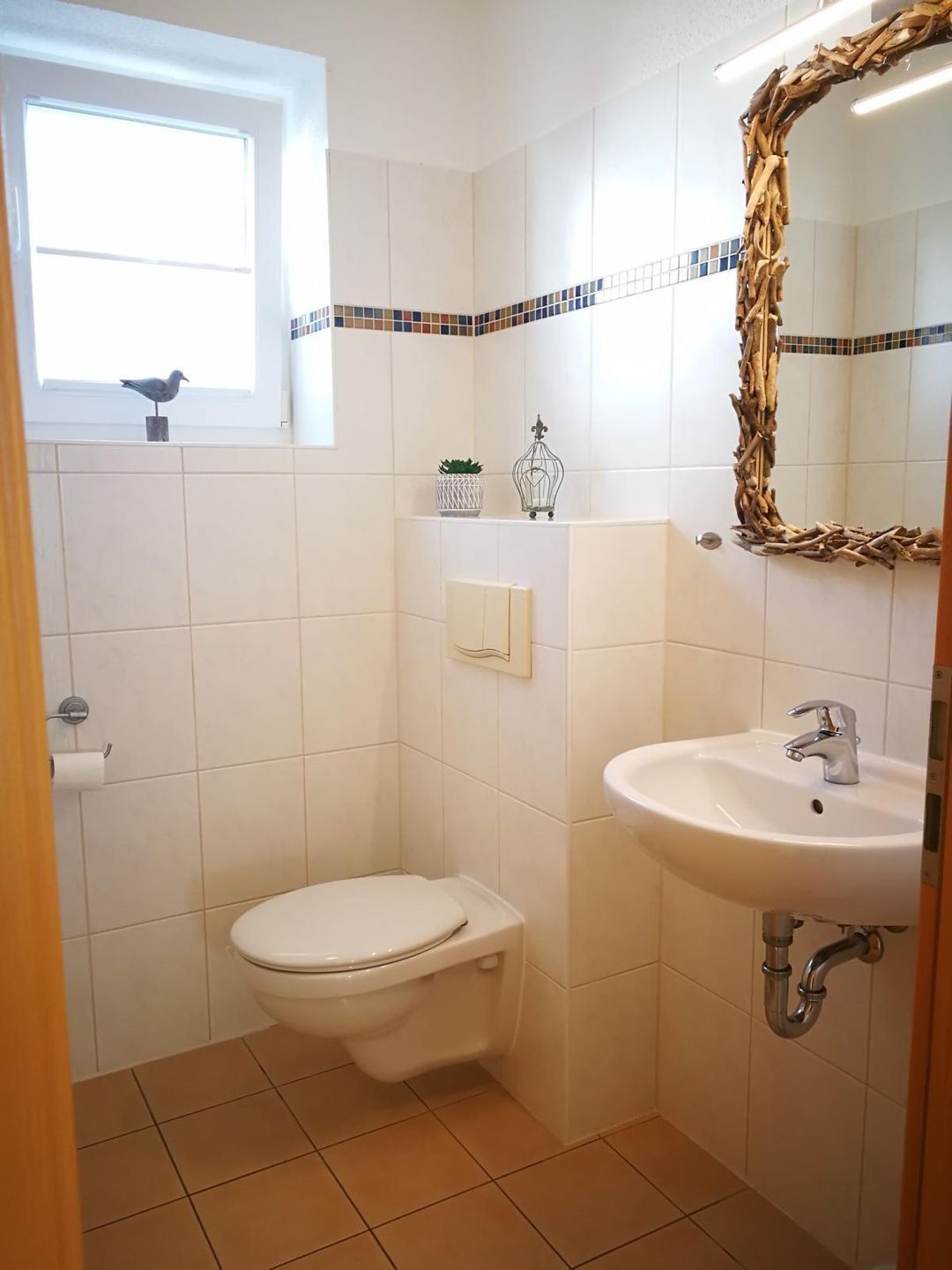 A small bathroom with a toilet, sink, and a window.