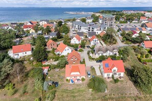 An aerial view of a coastal residential area with houses, some with solar panels, and a pier in the background. - Holiday home Boddenperle in Glowe - Holiday home "Boddenperle" (Glowe)