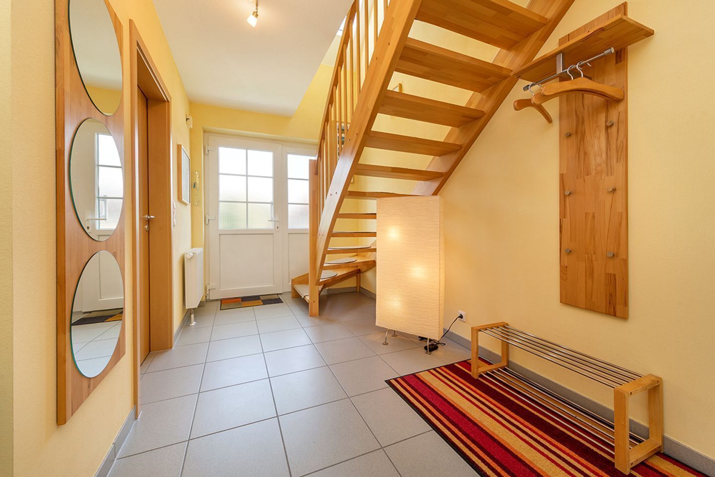 A hallway with a wooden staircase, a radiator, and a bench.