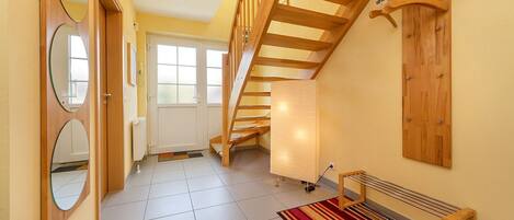 A hallway with a wooden staircase, a radiator, and a bench.