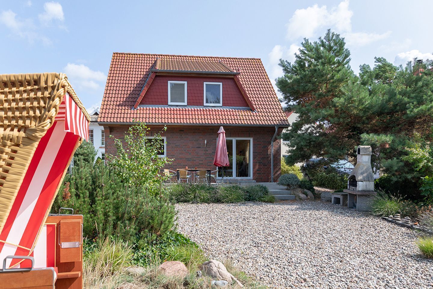 Een herenhuis met een rood pannendak, een bakstenen gevel en een grindpad.