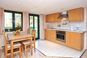 A kitchen with wooden cabinets, a stove, and a dining area with a table and chairs.