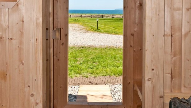 Uma cabana de madeira com vista para uma praia e um caminho de cascalho.