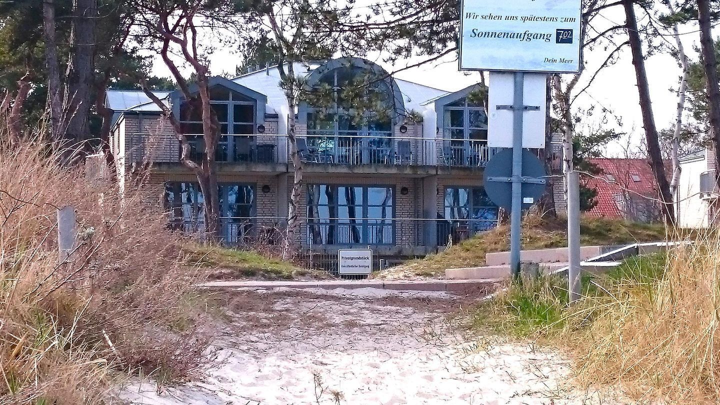 Een gebouw met een groot balkon, een bord met 'Sonnenaufgang' en een pad er naartoe.