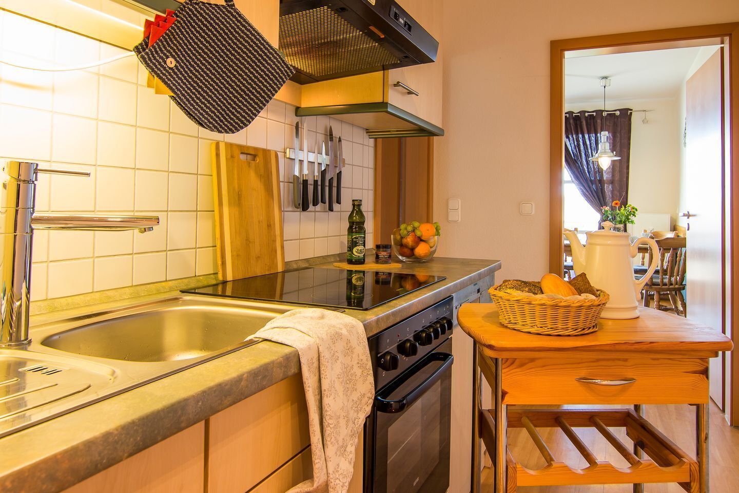 Une cuisine équipée d’un évier à deux bacs, d’appareils électroménagers en acier inoxydable et d’une table en bois sur laquelle se trouve un panier de pain.
