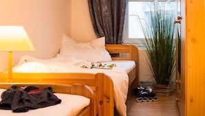 Um quarto aconchegante com cama de madeira, mesa de cabeceira com luminária, uma pequena planta e um sapateiro.