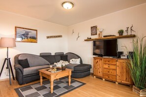 Un salon comprenant un canapé, une table basse, un téléviseur et un meuble.