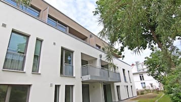 Un immeuble résidentiel moderne à plusieurs étages, doté de balcons et de grandes fenêtres.