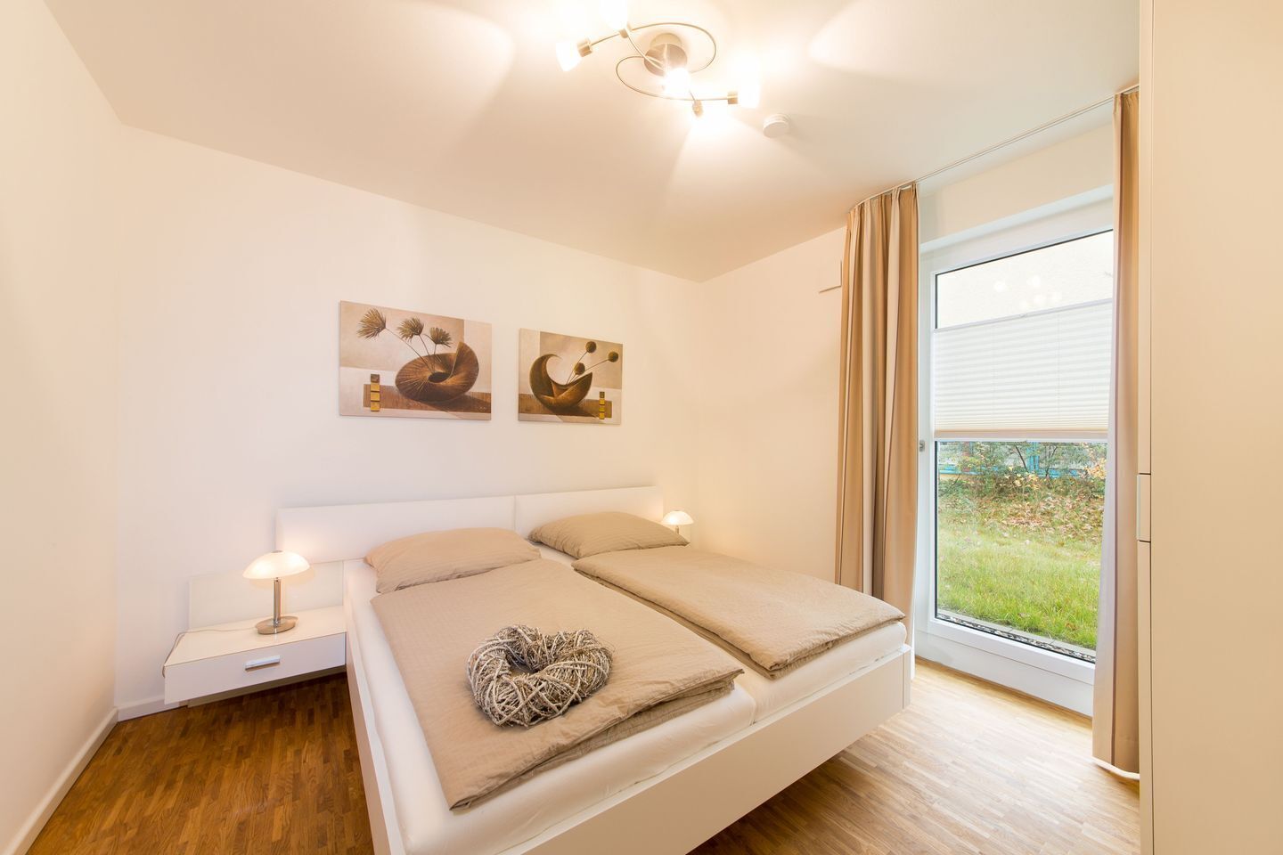 A bedroom with a bed, bedside tables, and two wall-mounted paintings.