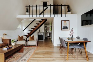 A spacious living area with a wooden staircase, a dining table with chairs, and a sofa set. - Modern A-Frame Near Frankenmuth & Bay City (Essexville)
