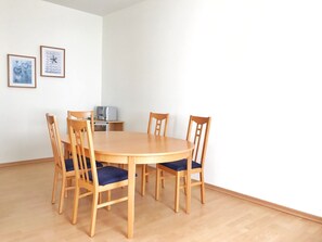 Une table de salle à manger ronde en bois, avec six chaises, un four à micro-ondes et deux tableaux encadrés accrochés au mur.