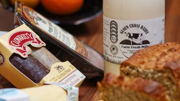 A table with sliced bread, a bottle of milk, a box of cheese, and a bowl of fruit.