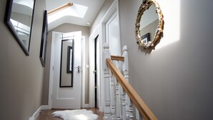 Een trap met witte leuningen en een houten handrail, leidend naar een deur met een witte deurmat.