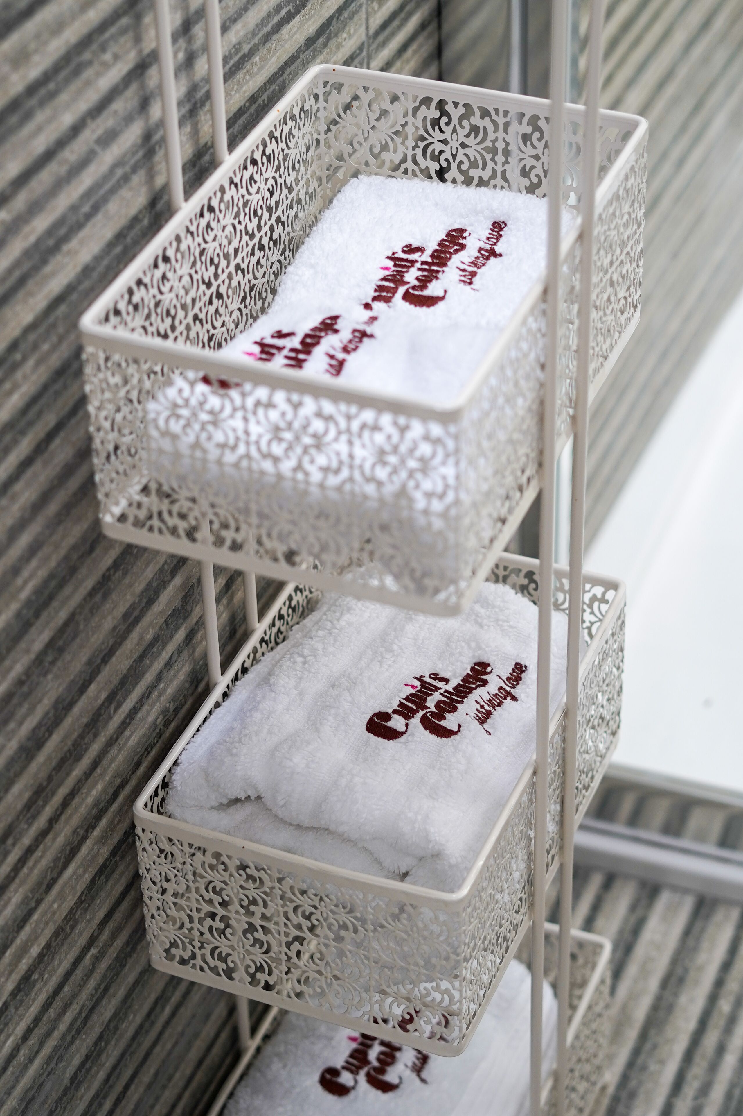 Three white, intricately designed metal baskets with towels, each labeled with a different message.