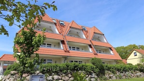 A multi-story building with a red-tiled roof and balconies.