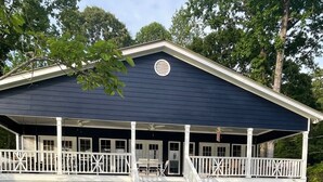A two-story building with a dark blue exterior, white railings, and a stone pathway leading to the entrance. - Peaceful lake house with private boat ramp and 2 docks (Jacksons' Gap)