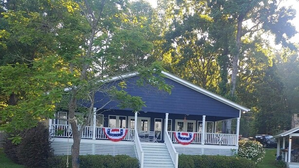 A dock leading to a house with a porch decorated with flags. - Peaceful lake house with private boat ramp and 2 docks (Jacksons' Gap)