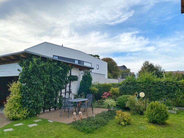 Una casa moderna con un patio, mobiliario exterior y jardín.