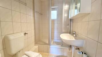 Een badkamer met toilet, wastafel en douche.