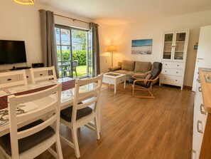 Ein modernes Wohnzimmer mit Essbereich, einem Fernseher, einer Couch und einem Schrank.