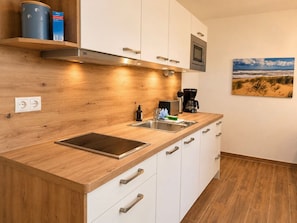 Una cocina moderna con encimera de madera, pileta de acero inoxidable y microondas.