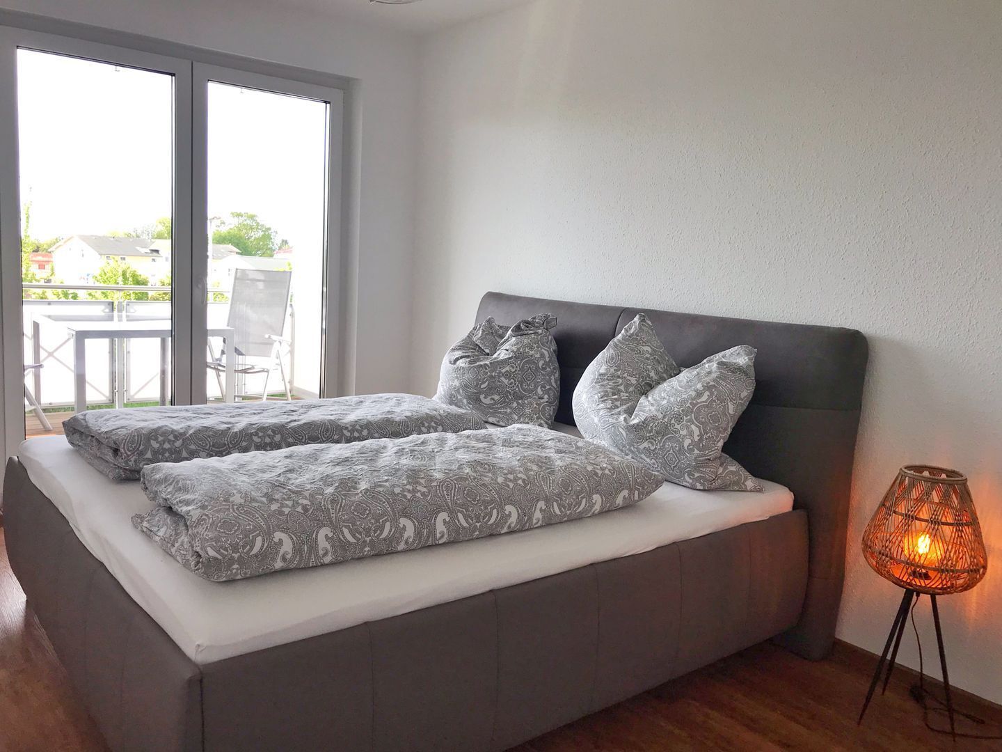 Ein modernes Schlafzimmer mit einem großen Bett, einem Balkon und einer Stehlampe.