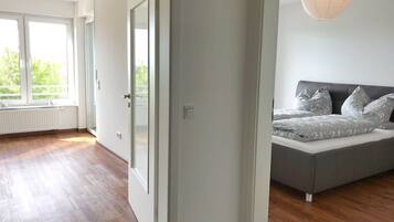 A modern bedroom with a large window, a bed with patterned bedding, and a hanging light fixture.
