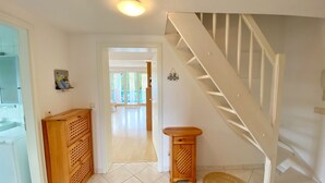 A hallway leading to a staircase with a white railing, a wooden bench, and a mat on the floor. - Ferienwohnung "osterholz" (Baabe)